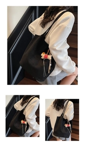 Detail of black suede tote bag with dog plush charm shown in a daily commute setting