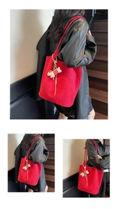 Detailed macro view of a large red suede tote bag with a cute white puppy pendant detail