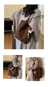 Detailed view of deep brown faux suede tote bag with a cute bear charm on shoulder strap