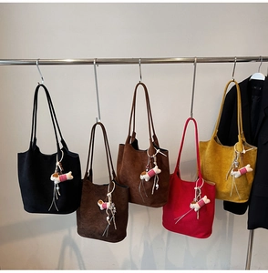 Row of colorful suede tote bags in various autumn shades with cute plush dog pendants