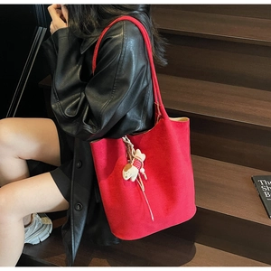Detail of red suede tote bag with dog charm on person wearing black leather jacket