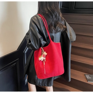 Detail of red suede tote bag featuring a cute dog pendant and large capacity design