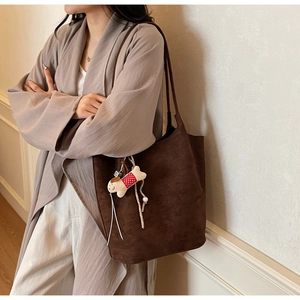Detail of dark brown suede tote bag with a cute dog bone charm for daily commute