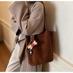 Detail of dark brown suede tote bag with cute bone pendant on long shoulder strap