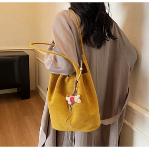 Detail of ginger suede tote bag with slim shoulder strap and small dog charm on a model