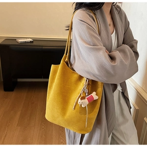 Large yellow suede tote bag with dog charm shown on shoulder for daily commute style