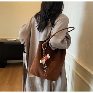 Brown suede tote bag detail featuring long shoulder straps and cute dog charm decoration