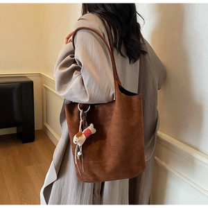 Close-up of brown suede tote bag with a cute plush puppy pendant detail