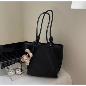 Detail of black lychee grain tote bag with knotted straps and cute bear charm pendant