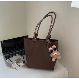 Detail of brown faux leather tote bag with lychee texture and knot shoulder strap design
