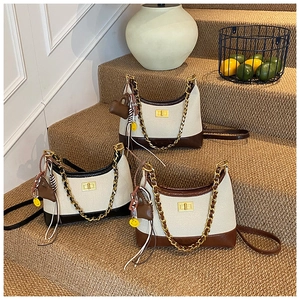Three canvas and leather hobo bags with gold chain details on minimalist stairs