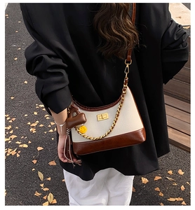 Detailed outdoor view of canvas patchwork crossbody bag with chain strap and charms