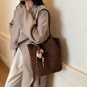 Deep brown suede tote bag with a cute bear charm, worn with a beige trench coat