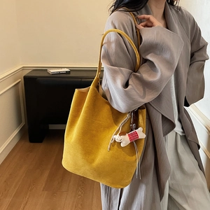 Minimalist large yellow suede tote bag with a cute spotted puppy charm on a model