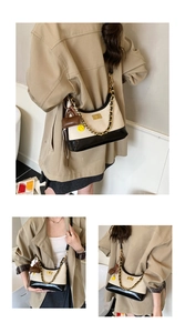 Detail of beige and black half-moon bag with gold chunky chain and cute charms