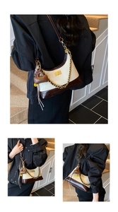 Detail of hobo bag with gold chain, heart charm, and contrast canvas leather textures
