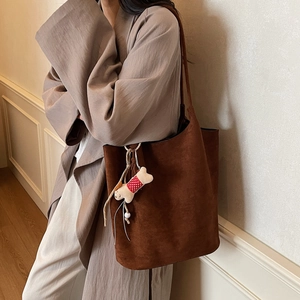 Brown suede tote bag for women with bone plush charm on khaki coat minimalist style
