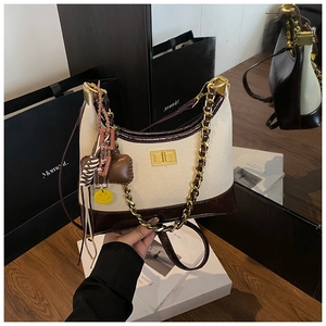 Close-up of canvas and brown leather crossbody bag with gold chain and charms