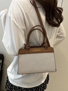 Sac fourre-tout minimaliste en toile avec garniture en cuir marron porté à l'épaule