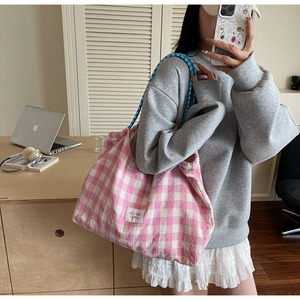 Detail of pink plaid canvas tote bag with blue woven rope handles in a lifestyle setting