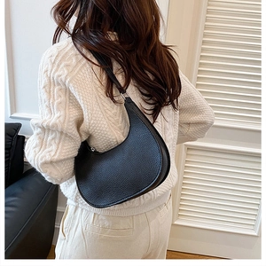 Black lychee leather hobo bag worn by a model in a cozy indoor lifestyle setting