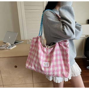 Detailed view of pink and white checkered tote bag with woven shoulder strap and snap closure