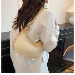 Detail of champagne gold crescent bag showing luxury lychee leather texture and silver buckle