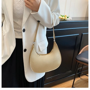 Detail of lychee pattern leather texture on beige crescent shoulder bag with zipper