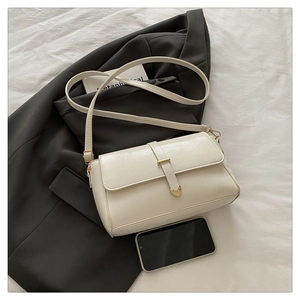 Detail of cream white PU leather crossbody bag with golden heart clasp and slim strap
