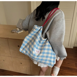 Détail du sac cabas à carreaux bleus avec bandoulière en corde rose et étiquette tissée
