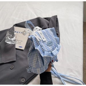 Dettaglio dello zaino in tela a quadri blu con bordi in pizzo e stemma fashion