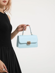 Elegant light blue square handbag with gold metal clasp carried by model in black dress
