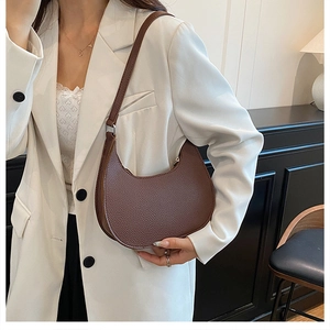 Brown crescent shoulder bag in lychee pattern leather styled with a white blazer suit