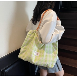 Détail du sac cabas à carreaux verts avec bandoulière tissée et étiquette décorative