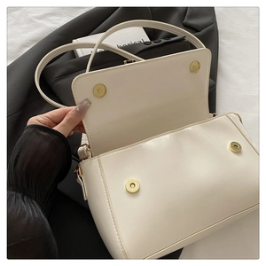 Detail of white leather handbag showing double magnetic snap closures and fine stitching