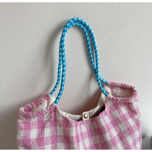 Detail of pink plaid tote bag featuring blue braided handles and magnetic metal clasp