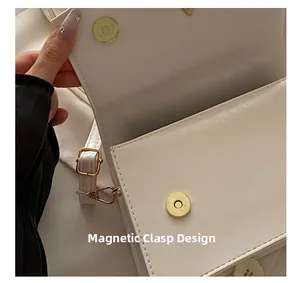 Close-up of white leather bag featuring magnetic clasp closure and gold metal hardware