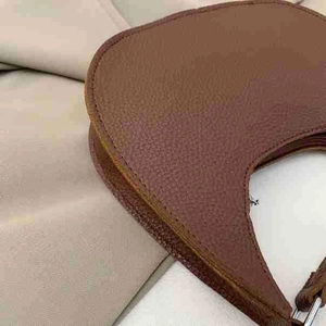 Detailed close-up of premium brown lychee grain leather handbag with professional edge finishing