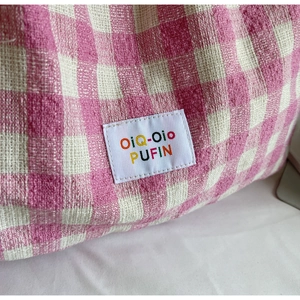 Close-up of pink checkered fabric texture and OiQ-Oio PUFIN embroidered label on tote bag