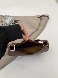 Detail of brown pebbled leather bag interior with silver zipper and brown fabric lining