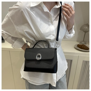 Minimalist black woven handbag styled in a lifestyle home setting with silver horseshoe lock