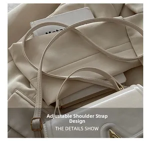 Detail of adjustable shoulder strap with gold metal buckle on white faux leather bag