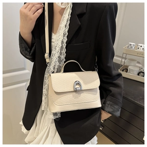 Detail of off-white crossbody bag with woven texture and silver horseshoe buckle