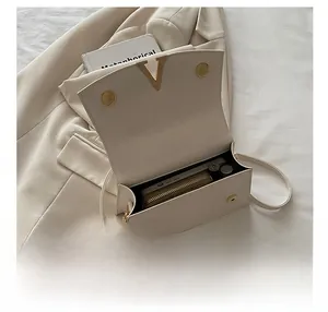 Detail showing the internal storage capacity of the beige square bag with gold V buckle