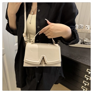 Detail of cream white leather handbag featuring a signature gold V-shaped metal buckle