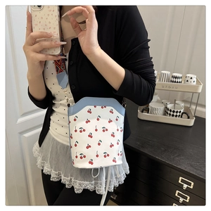 Detail of cherry print handbag with vibrant geometric jacquard woven shoulder strap