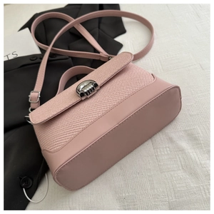 Detail of pink vintage tote bag featuring woven texture flap and silver metal spring lock