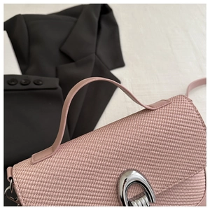 Detail view of pink woven texture handbag with polished silver horseshoe metallic buckle