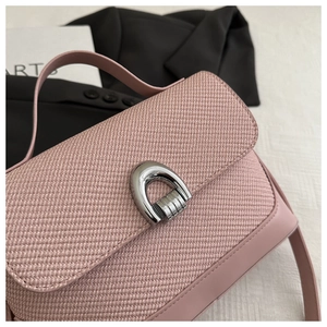 Detail of dusty rose handbag featuring woven texture and silver U-shaped metal buckle