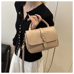 Detail of a beige leather handbag featuring a gold buckle and adjustable shoulder strap